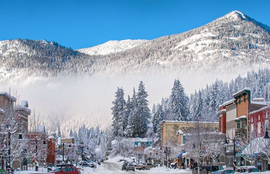 Snowy mountain town main street in winter beneath forested slopes
