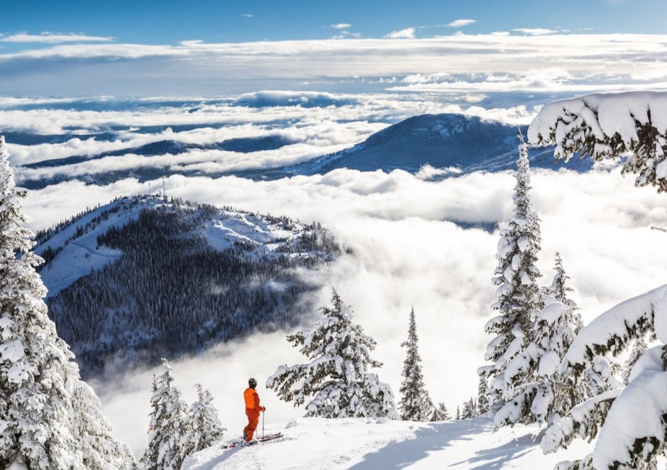 Aerial view of an alpine ski resort with groomed runs on a forested mountain